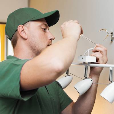 A Honey Do Service handyman fixing a light fixture