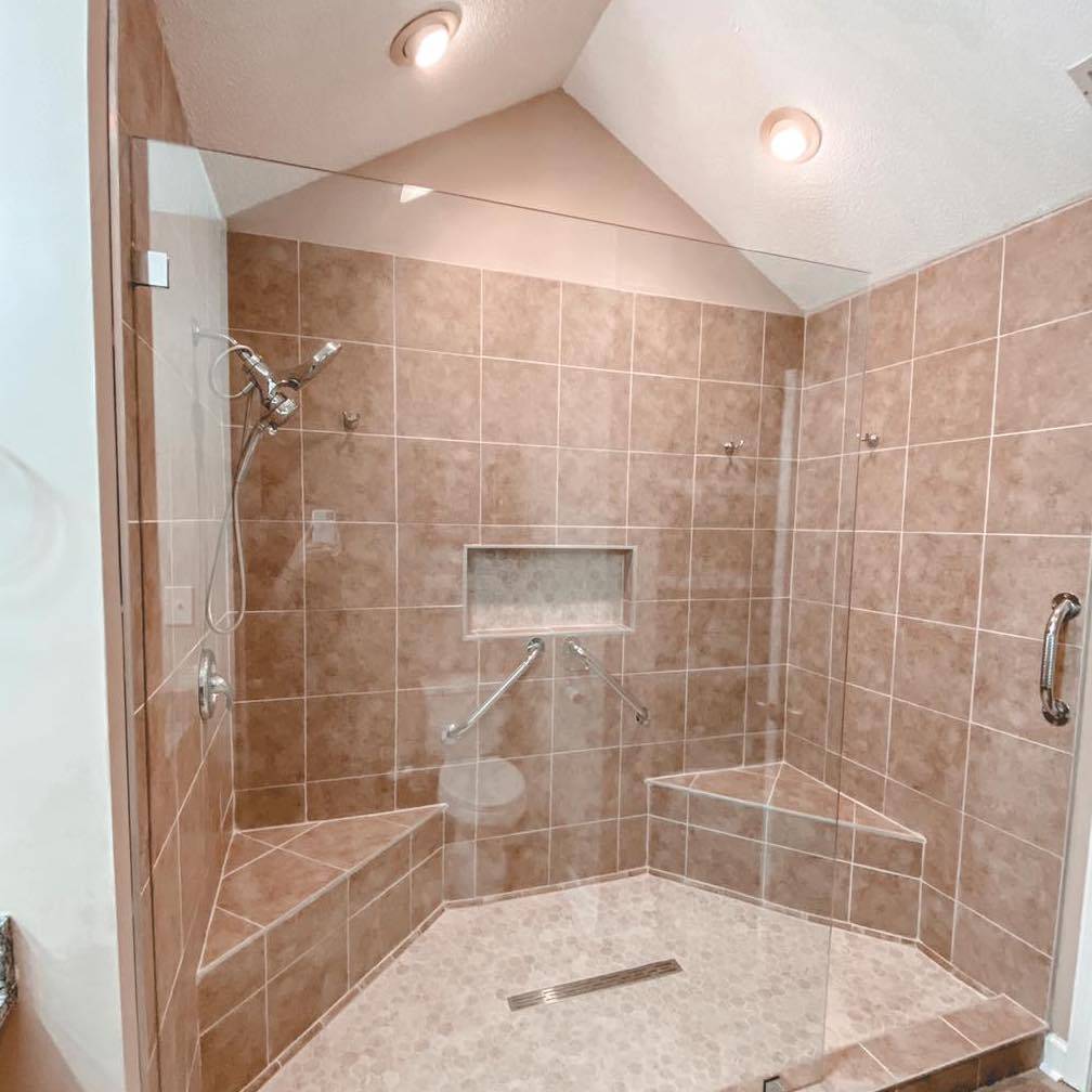 A remodeled shower and bathroom, featuring a walk in shower with support rails